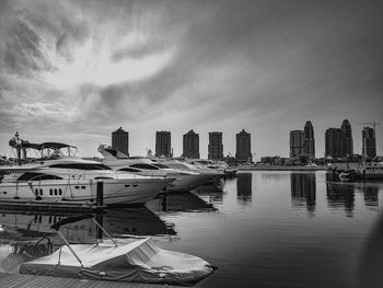 Boats moored in harbor against buildings in city