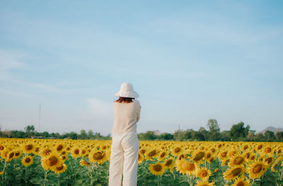 Rear view of person standing in sunflower field