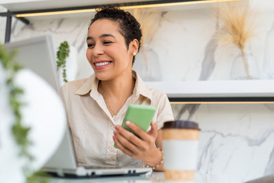 Woman looking at camera while sitting on table