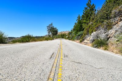 Surface level of road against clear blue sky