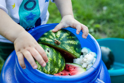 Midsection of boy by fruits in container