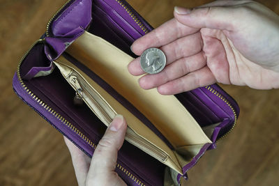 Cropped hand of woman holding purse with coin