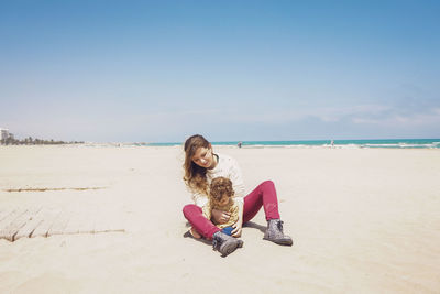 Portrait of young woman on beach against sky