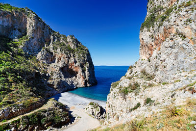 Scenic view of sea and rocks against blue sky