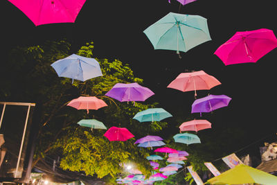 Low angle view of multi colored umbrellas hanging on tree