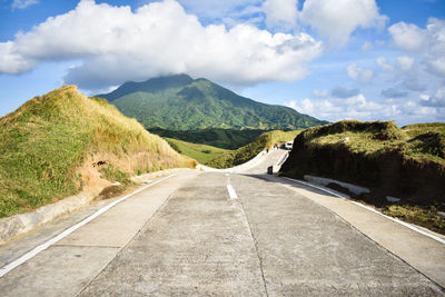 Road leading towards mountains against sky