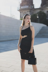 Portrait of young woman standing in city