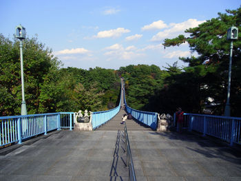 Footbridge amidst trees against sky