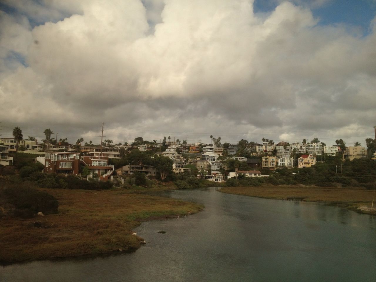 building exterior, architecture, built structure, sky, water, cloud - sky, cloudy, river, residential structure, residential building, city, house, residential district, cloud, cityscape, town, waterfront, tree, day, high angle view