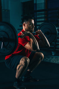 Male athlete exercising with barbell in gym