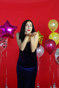 Full length of a young woman with red balloons