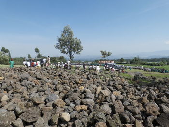 Group of people on rocks by road against sky