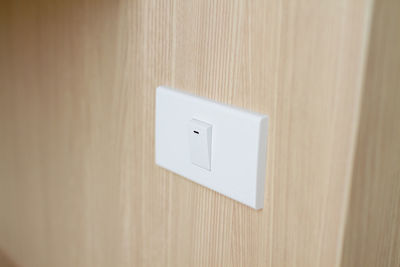 Close-up of light switch on wooden wall