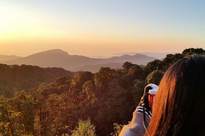Cropped image of woman photographing landscape during sunset