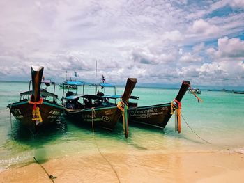 Boats moored on beach against sky