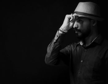 Young man looking away against black background