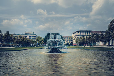 Fountain in city against sky