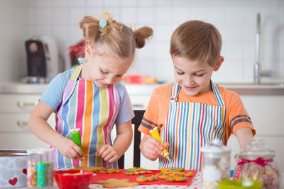 View of cute girl and boy preparing food at kitchen