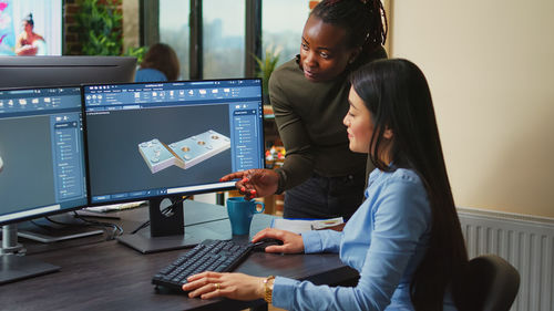 Side view of woman using laptop at office