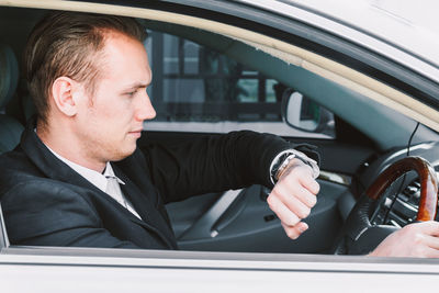 Businessman checking time while driving car