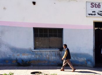 Full length of young man standing against building