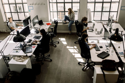 High angle view of coworkers working while female talking on phone in office