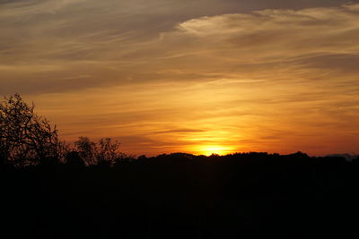 Silhouette landscape against orange sky