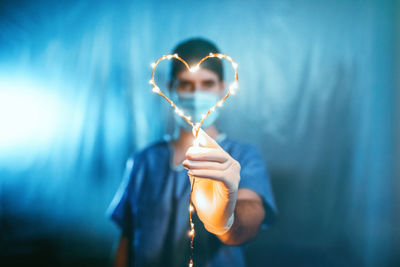 Midsection of man holding heart shape against blue background