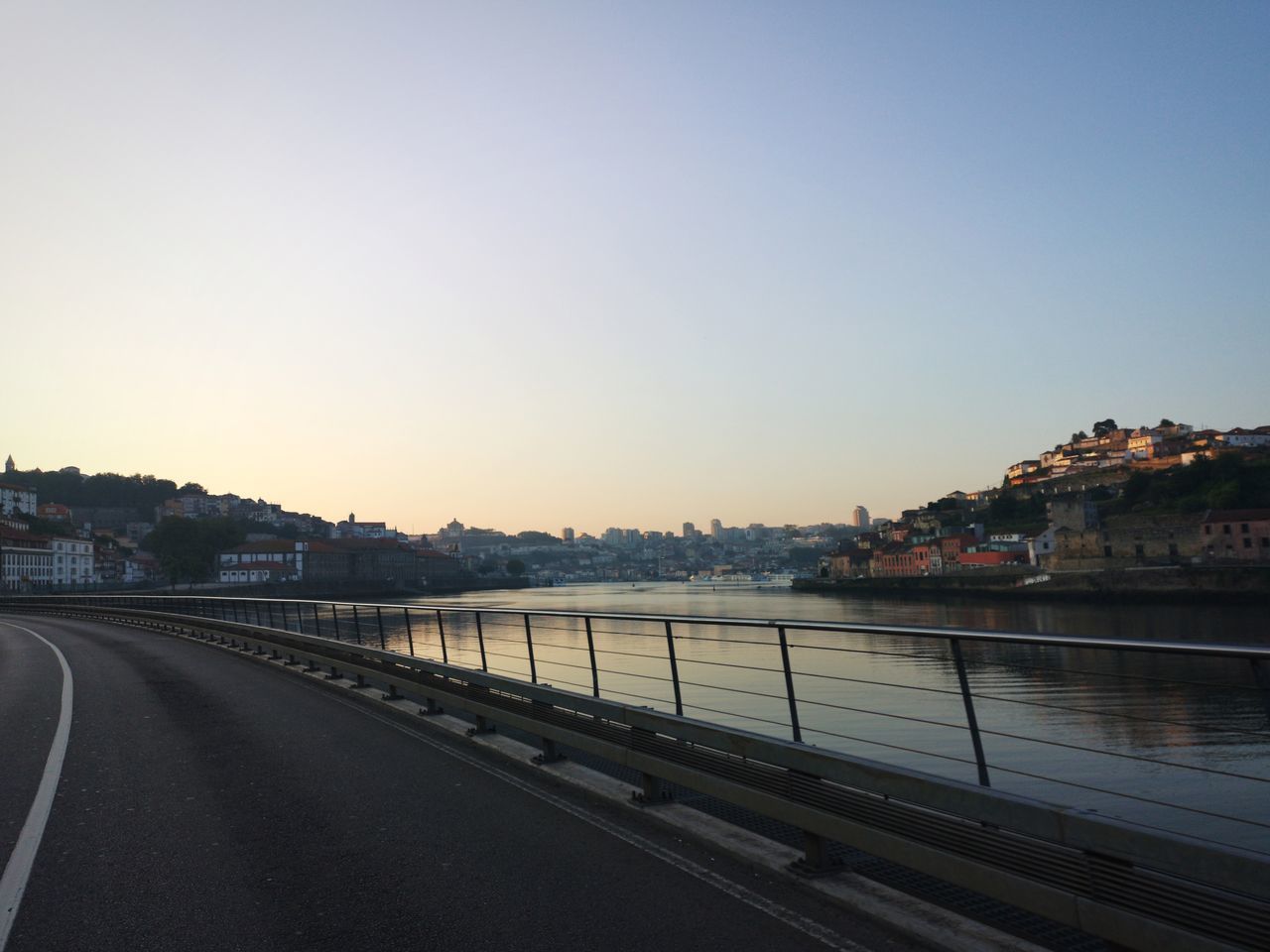 ROAD BY RIVER AND BUILDINGS AGAINST SKY