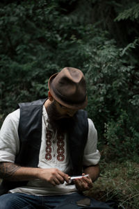 Midsection of man smoking while sitting outdoors