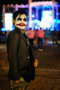 Portrait of young man with face paint standing in city at night