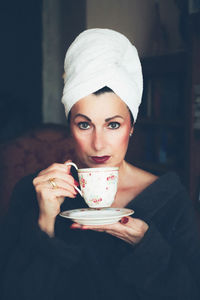 Portrait of woman drinking coffee while wearing robe