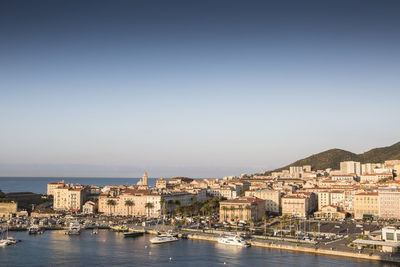 Buildings by sea against clear sky