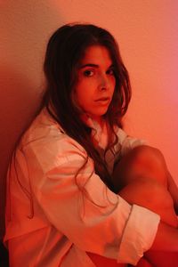 Portrait of young woman standing against wall