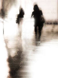 Rear view of silhouette people walking on rainy day