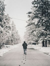 Rear view of man walking on snow covered road