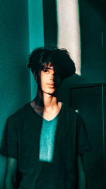 Young man looking away while standing against wall