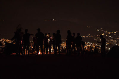Silhouette people at illuminated park against sky at night
