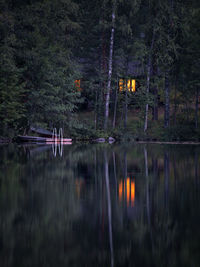 Reflection of trees and keinoja cottage in lake at summer night