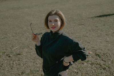 Portrait of young woman standing on field