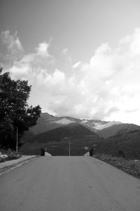 Road by mountains against sky