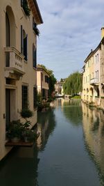 Canal amidst houses against sky