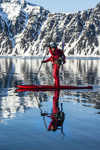 Woman paddles on sup board with skis in jan mayen