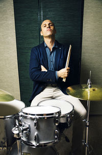 Portrait of confident drummer sitting with his drum kit