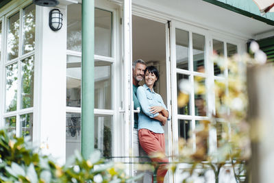 Happy heterosexual couple at doorway of house