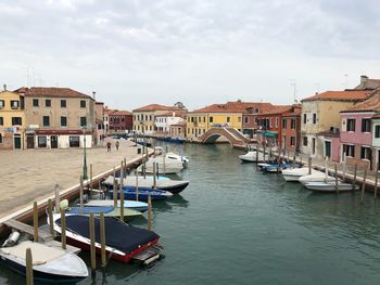 Boats moored in canal against buildings in city