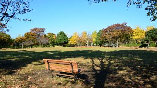 Empty bench in park against sky during autumn