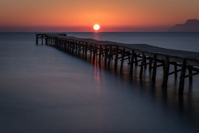 Pier over sea against sky during sunset