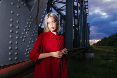 Woman in red standing near railway bridge