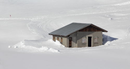 Snow covered houses by land and mountains against sky